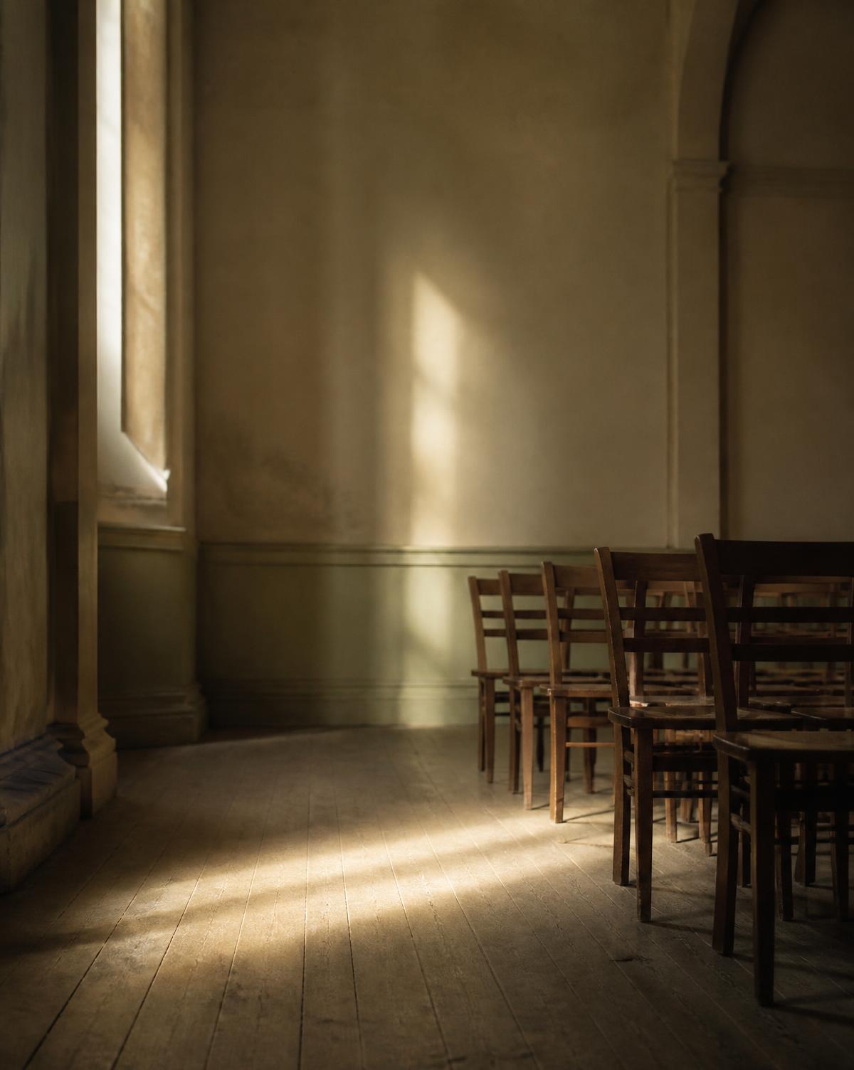 Wooden chairs in a quiet hall with morning light across the floor